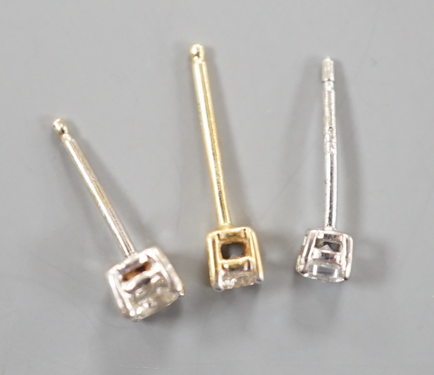 Two odd diamond set ear studs, the stones of various sizes and one paste set ear stud, gross weight 1.3 grams.